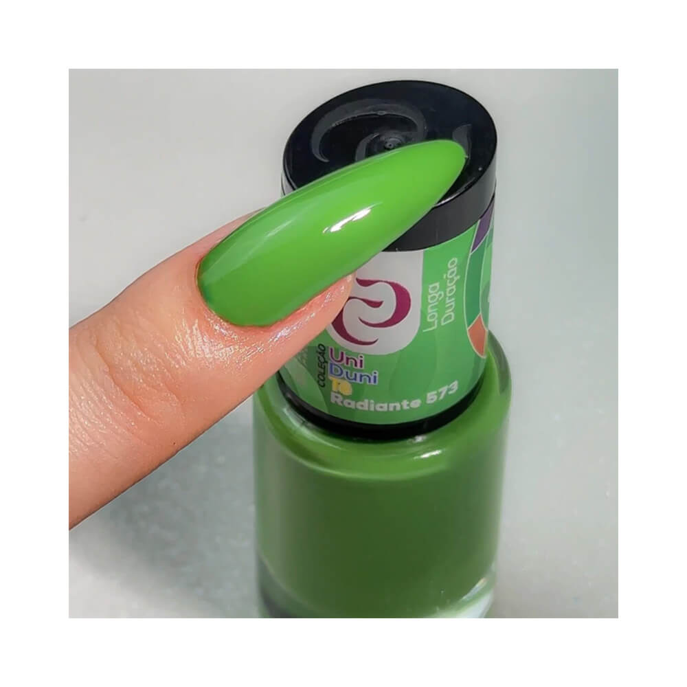 Unha longa pintada com esmalte verde da coleção Uni Duni Tê, cor Radiante 573, segurando o frasco do esmalte